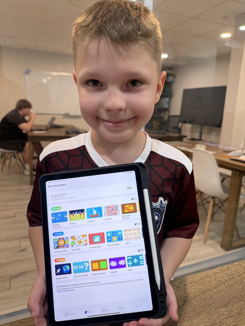 Happy child showing KidsBrain games on iPad